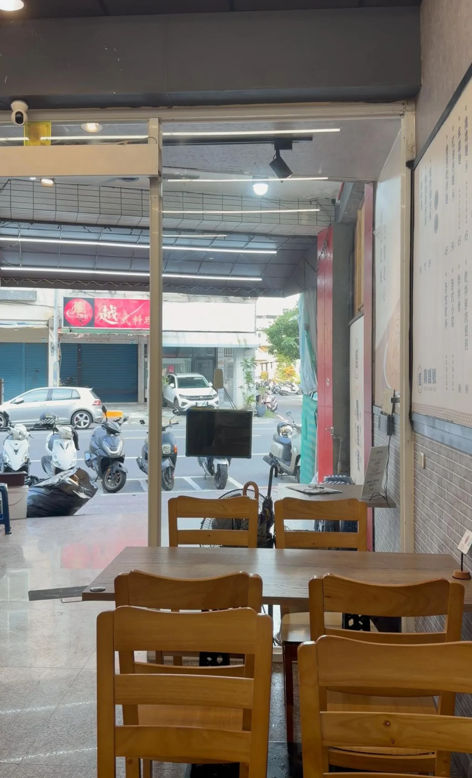 鼎盛號 三民店 店內木頭桌椅用餐區,空間明亮乾淨,牆上掛著菜單看板